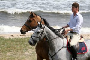 Peder rider på stranden med två hästar