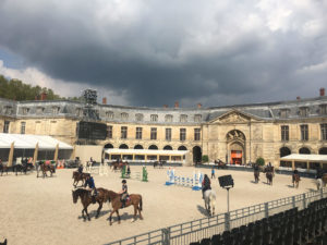 Många hästar och ryttare syns på bild med ett stort mörkt moln ovanför