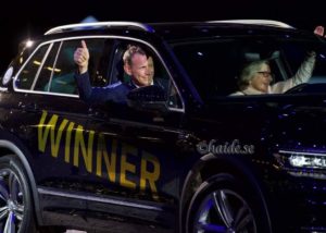 Peder och en dam vinkar från en bil med texten "winner"